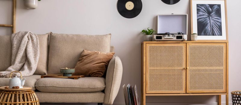 stylish-composition-living-room-interior-with-beige-sofa-pillow-plaid-coffee-table-rattan-commode-personal-accessories-beige-wall-mock-up-poster-template (1)